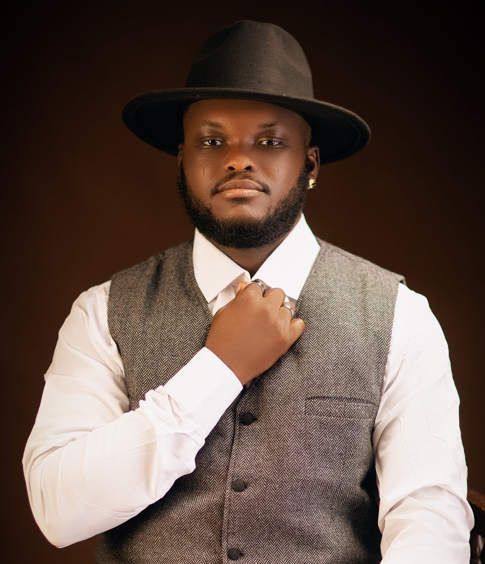 Ayoola Abiola in a grey waistcoat and black fedora